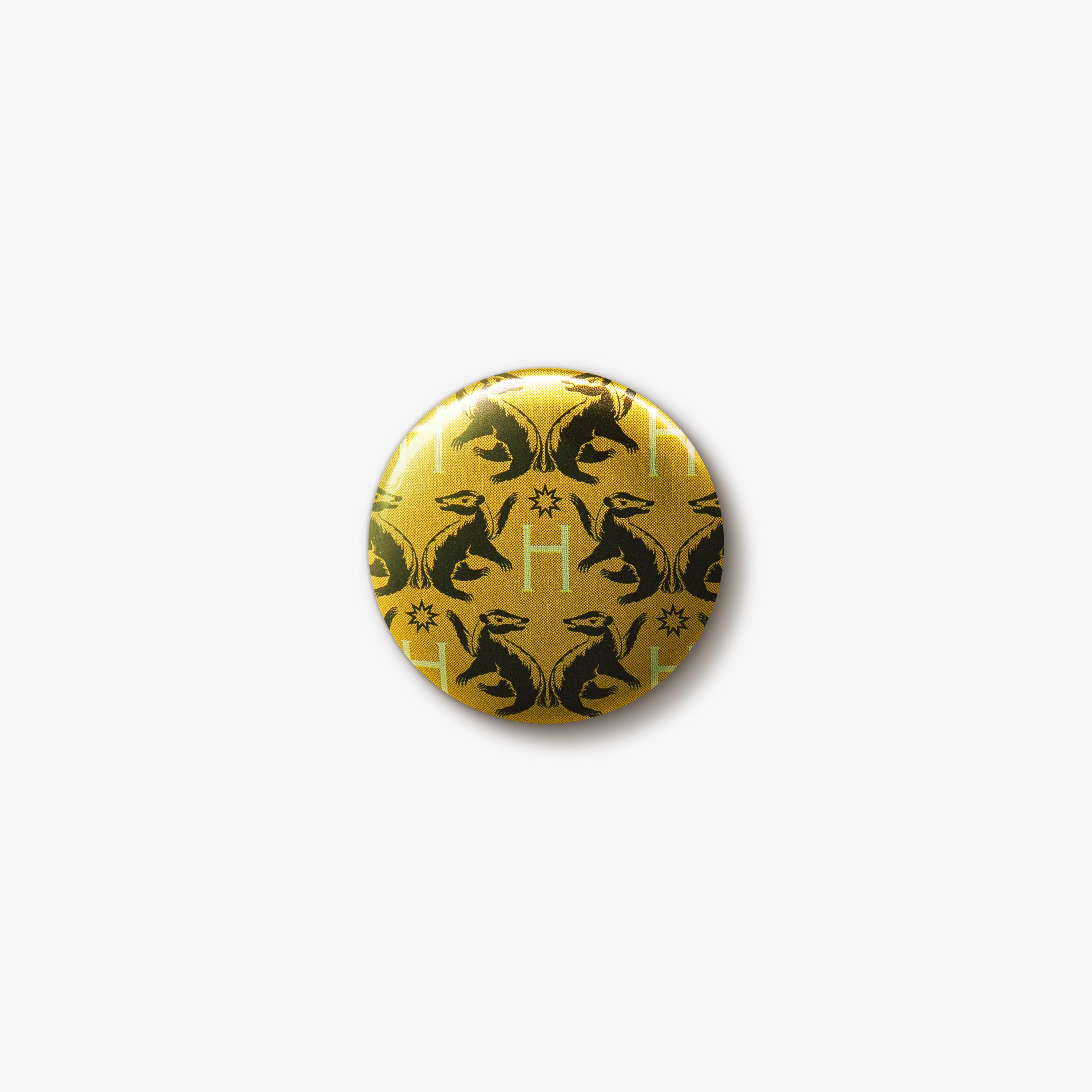 Yellow button badge with a repeating pattern of black Hufflepuff badger emblems and gold ‘H’ letters.
