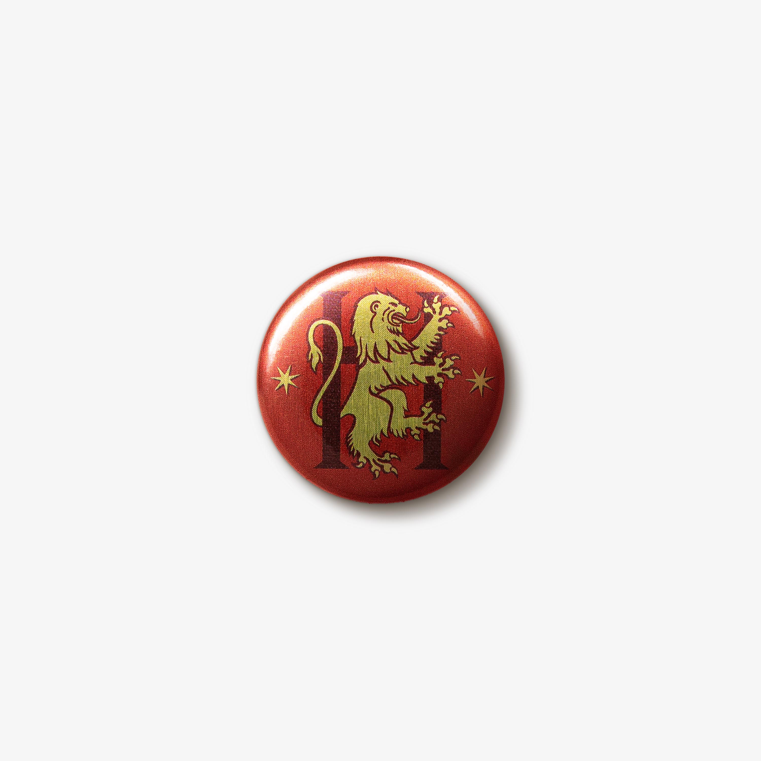 Red button badge featuring a golden Gryffindor lion emblem intertwined with a dark ‘H’ letter in the centre. There are two gold seven-pointed stars either side of the emblem.